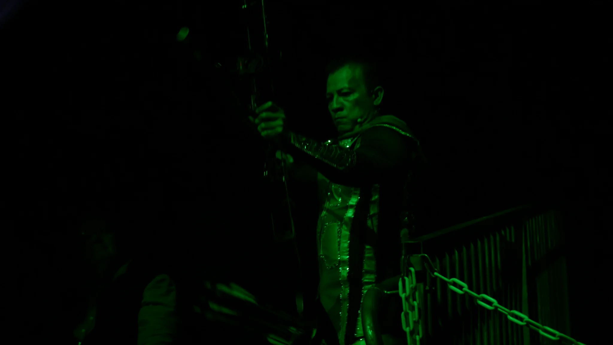 Archer performing beneath green stage light