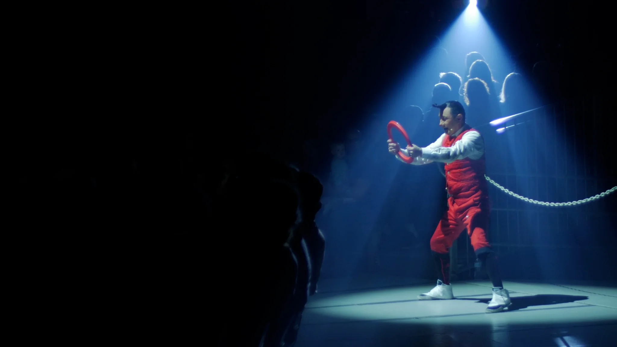 Circus performer standing beneath a blue spotlight