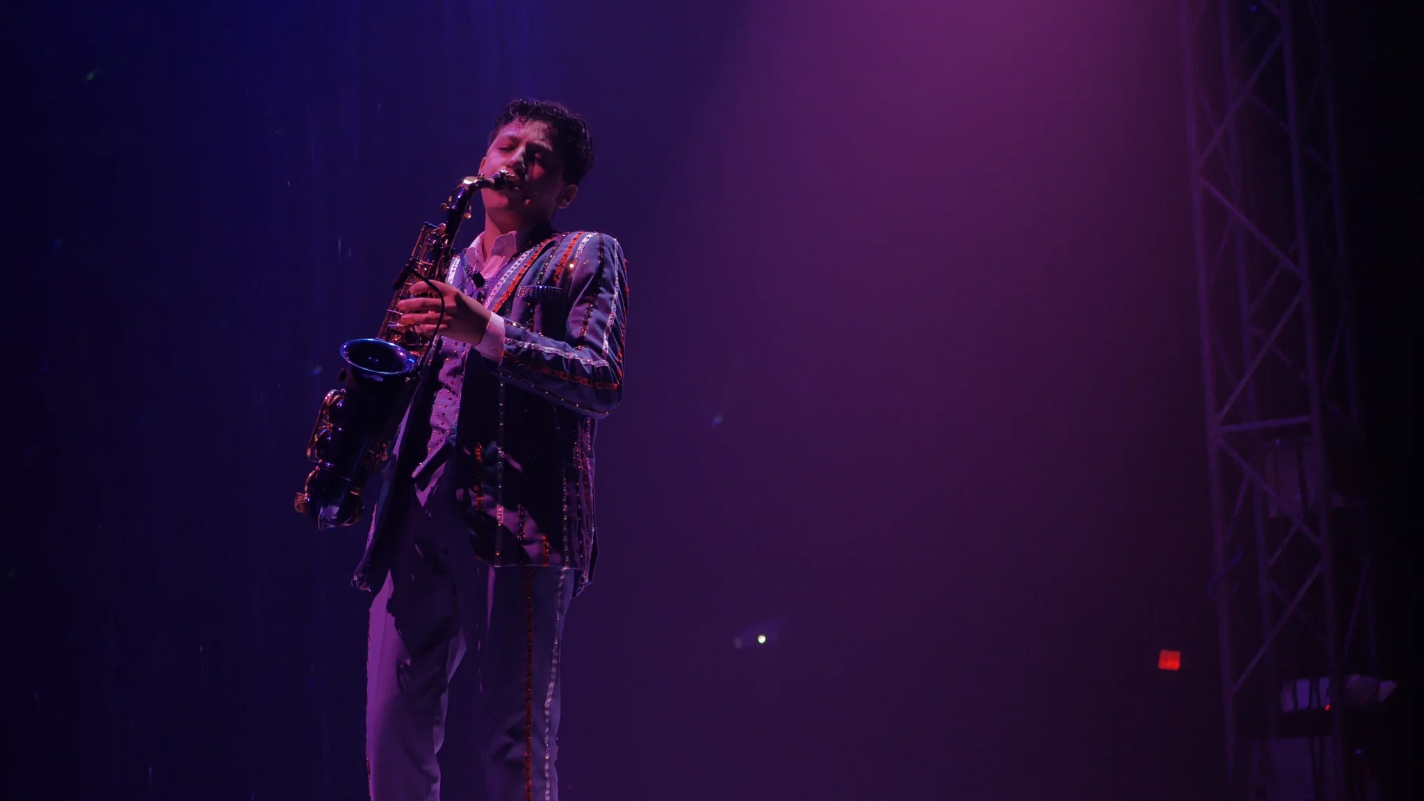 Saxophone performer beneath stage lighting